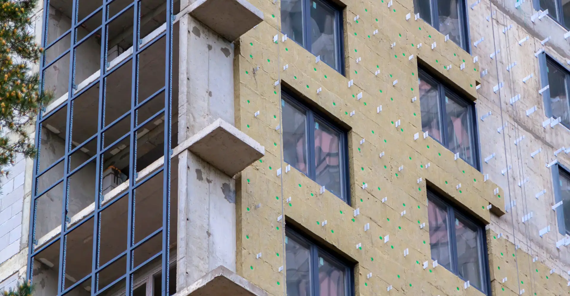 Installation of external wall thermal insulation with rock wool. Exterior passive house wall heat insulation with mineral wool. Insulation facade of multistory residential building. Energy efficiency